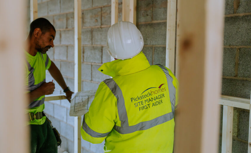 Two people reviewing plans outside a new build home.