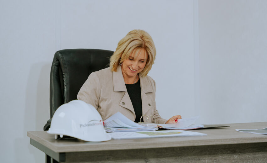 Woman reviewing paperwork at a Pickstock Homes desk.