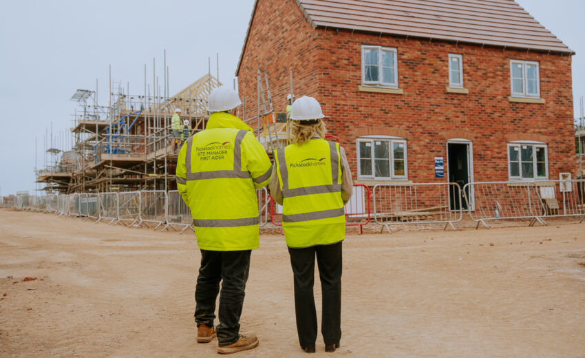 Two site visitors talking with a Pickstock Homes representative.