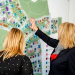 Two people reviewing a site plan on a wall display - Pickstock Homes