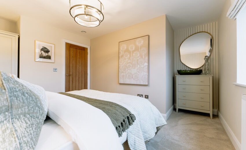 New build bedroom with arched headboard and bedside lamp.