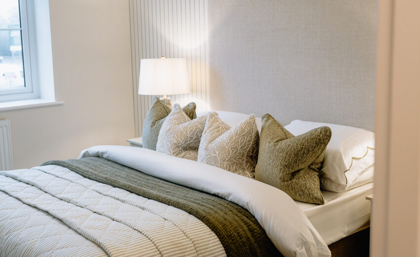 New build bedroom with patterned cushions and neutral bedding.