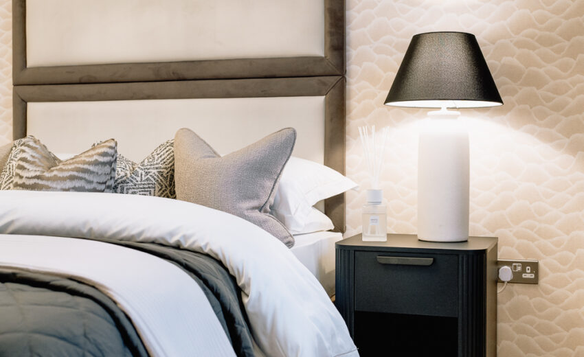 Bedroom in a new build with upholstered headboard and bedside lamp.