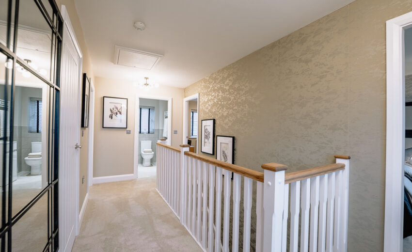 New build hallway landing with staircase and framed artwork.