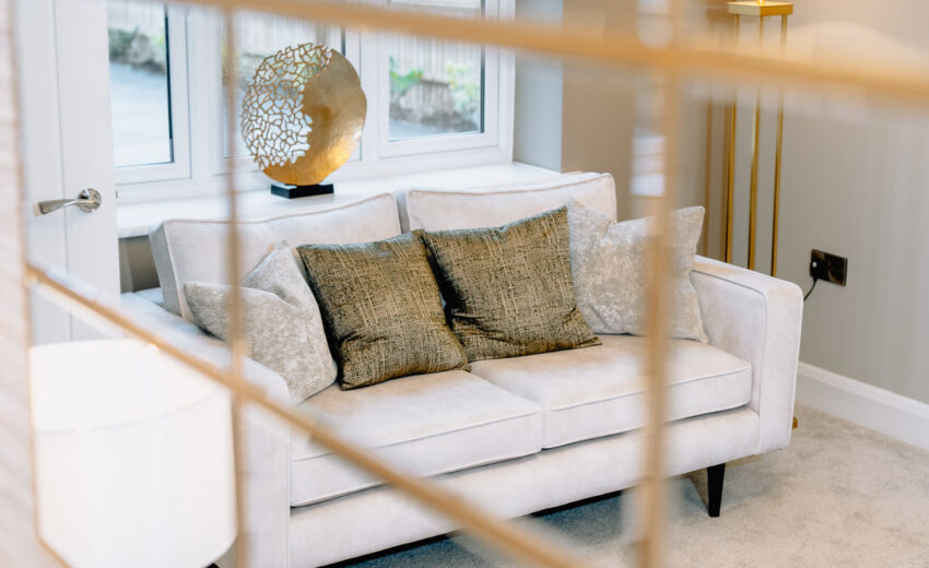 New build sofa close-up with cushions and mirror reflection.