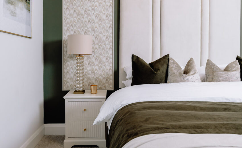 New build bedroom with upholstered headboard and bedside lamp.