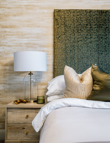 New build bedroom with bedside lamp and upholstered headboard.