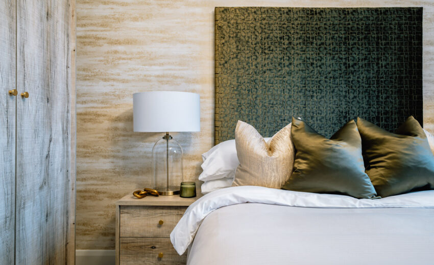 New build bedroom with bedside lamp and upholstered headboard.