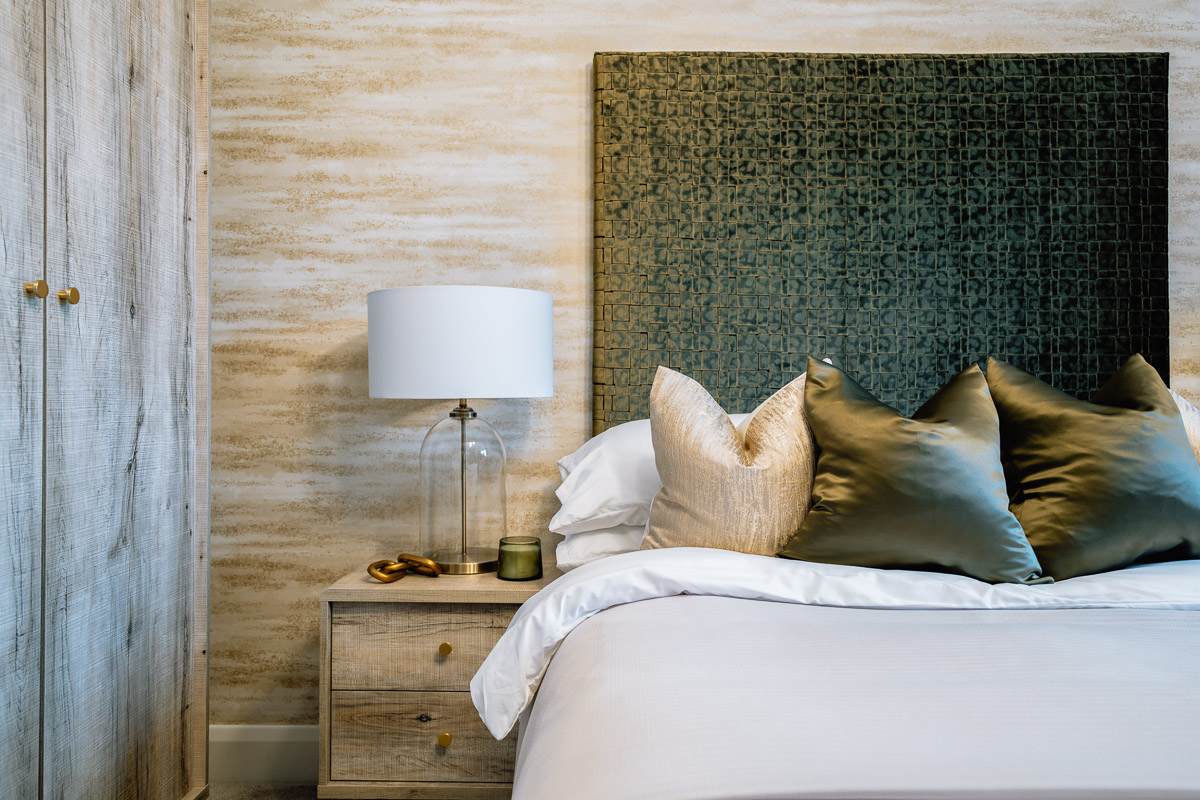 New build bedroom with bedside lamp and upholstered headboard.